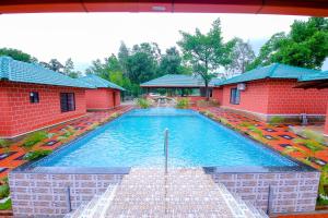 a large swimming pool in front of two red buildings at River Raga Nature Resort in Kārkāl