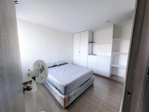 a white room with a bed and a fan at Bonito Aparatemnto con Piscina in Santa Marta