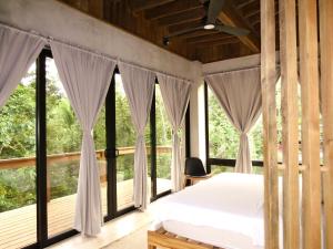 a bedroom with a bed and large windows at Villa con piscina privada, West Bay Roatan in Coxen Hole