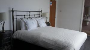 a bedroom with a bed with white sheets and pillows at Halfway House Hotel in Larne