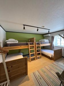 a room with bunk beds and a green wall at The Bunkhouse Hakuba by Mr T in Hakuba