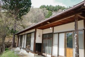 a house in the woods with a porch and windows at 0site house in Hokuto +9 photos