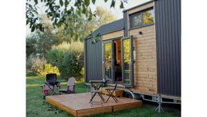 a tiny house on a trailer with a wooden deck at Vilasini Hut by Tiny Away in Great Horkesley
