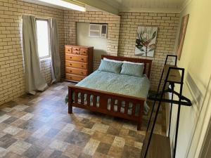 a bedroom with a bed and a dresser and a window at 109 Meson Street Gayndah in Gayndah