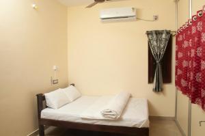 a small room with a bed and a air conditioner at Misha Residency in Virāmpattinam