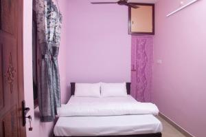 two beds in a room with purple walls at Misha Residency in Virāmpattinam