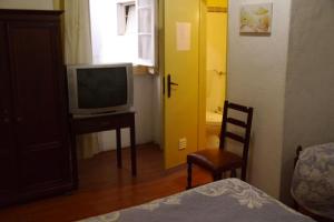 a bedroom with a television and a desk with a chair at Residencial Luz in Tomar