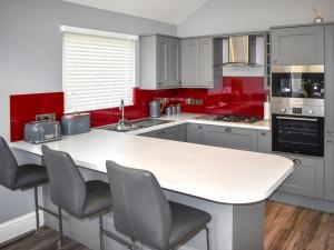 Una cocina con paredes rojas y encimera blanca. en Oak Park Two - Uk50063, en Tiverton