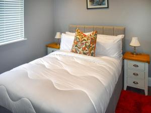 1 dormitorio con 1 cama blanca con 2 mesitas de noche y 2 lámparas en Oak Park Two - Uk50063, en Tiverton