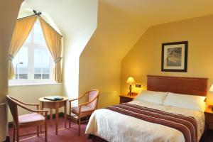 1 dormitorio con 1 cama, mesa y sillas en Fitzgeralds Hotel, en Bundoran
