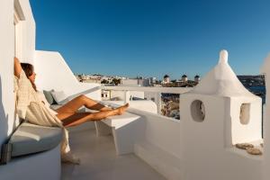 a woman sitting on a balcony looking out over the ocean at Little Venice Suites in Mýkonos City