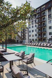 a swimming pool with tables and chairs next to a building at Apartman Njegoš Lux Titova vila in Palisad