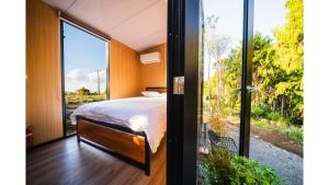 a bedroom with a bed and a sliding glass door at The Mini Mountain Hut 2 by Tiny Away in Egmont Village +8 photos
