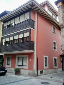 a red building with a balcony on the side of it at Apartamentos Cotiello in Llanes