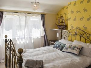 a bedroom with a bed and a yellow wall at Selkie Cottage in Corton