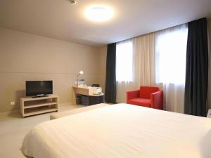 a hotel room with a bed and a red chair at Jinjiang Inn Yueyang Railway Station in Yueyang