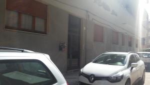 twee witte auto's geparkeerd voor een gebouw bij Casa Vacanze Gigì in Alghero