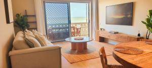 una sala de estar con un sofá y una mesa en Direct Ocean Front Apartment, en Redcliffe