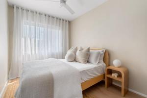 a bedroom with a bed with white sheets and a window at Direct Ocean Front Apartment in Redcliffe