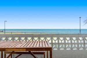 a wooden picnic table sitting on top of a beach at Direct Ocean Front Apartment in Redcliffe