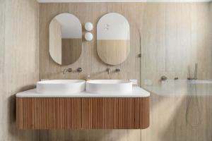 a bathroom with two sinks and two mirrors at Direct Ocean Front Apartment in Redcliffe