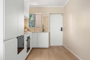 a kitchen with white appliances and a wooden floor at Direct Ocean Front Apartment in Redcliffe +31 photos