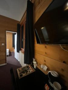a room with a large tv on the wall at Hôtel Au Feu De Bois in Autrans