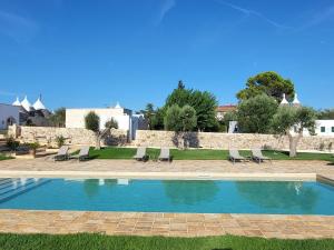 a swimming pool with chairs and a wall at Trulli Capomazza in Noci