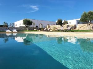 a large pool of water with chairs and a building at Trulli Capomazza in Noci
