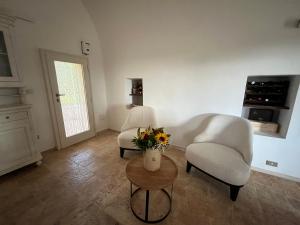 a living room with two chairs and a table with flowers at Trulli Capomazza in Noci