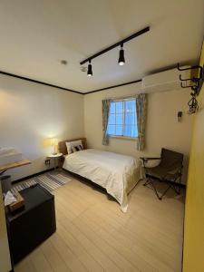 a bedroom with a bed and a desk and a window at The Bunkhouse Hakuba by Mr T in Hakuba +8 photos