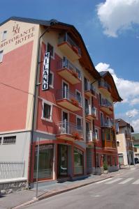 een rood gebouw met balkons in een straat bij Hotel Milano in Asiago