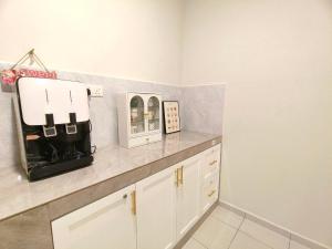 une cuisine avec des armoires blanches et un comptoir dans l'établissement Cozy Batu 4-Game, Neflix, Water Dispenser, à Keluang