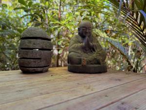 a statue of a monk sitting on a wooden table at Nikau Sanctuary in Raglan