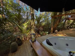 a bath tub sitting on a wooden deck in a forest at Nikau Sanctuary in Raglan