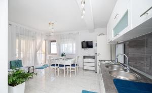 a kitchen with a sink and a table with chairs at Apartments Sanja in Zaton