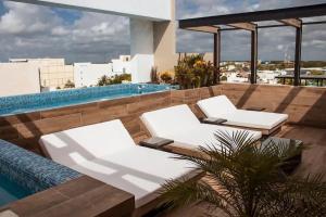 two white lounge chairs next to a swimming pool at George Luxury Condo in Playa del Carmen