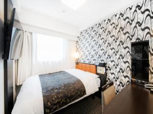 a hotel room with a bed and a wall at APA Hotel Hakata Higashihieekimae in Fukuoka