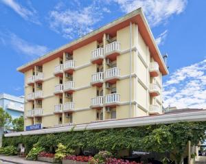 a large yellow building with balconies and flowers at Hotel Nevada in Bibione