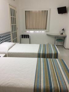 a hotel room with two beds and a television at Conect Smart Salvador by Accor in Salvador