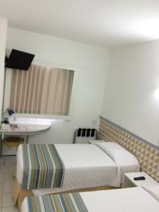 a hotel room with two beds and a television at Conect Smart Salvador by Accor in Salvador