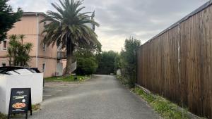 an empty street with a palm tree next to a fence at Kyriad ECO - Anglet Côte Basque in Anglet
