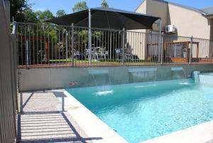 a swimming pool with a fence and an umbrella at Highfields Motel Toowoomba in Highfields