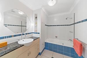 a bathroom with a sink and a tub and a mirror at Beachside 2 bed 2 bath unit in Townsville +4 photos