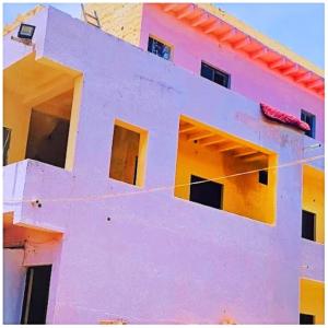 德瓦尔卡Hotel Yuvraj AC OR NON AC BOTH ROOM Dwarka Gujrat的粉红色和黄色的建筑