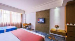 a bedroom with a bed and a tv on a wall at Downtown Hotel in Zhuhai