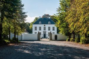 a white house with a black roof and a driveway at Het Witte Kasteel in Loon op Zand