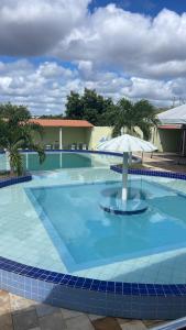 a large blue swimming pool with an umbrella at Pousada e Restaurante Vale Verde in Cabaceiras