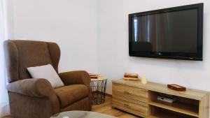a living room with a chair and a flat screen tv at Ifigenias apartment in Áyios Pétros