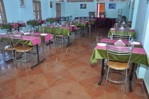 a room with tables and chairs with pink and green tables at Parkinternational in Kovalam